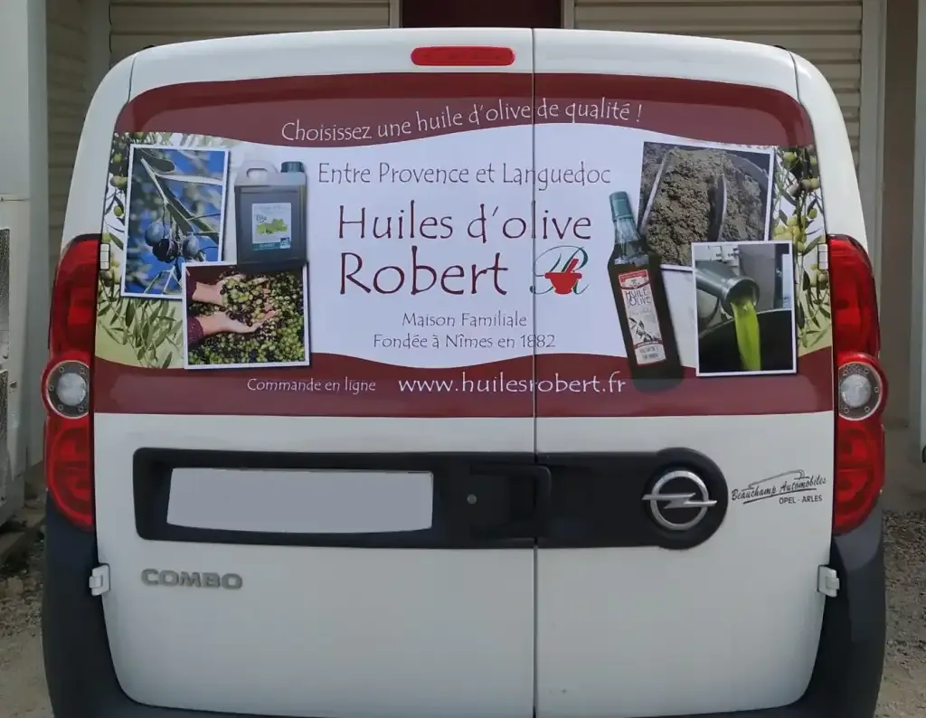 Marquage publicitaire bordeaux et blanc posé sur un utilitaire pour une maison d’huiles d’olive.