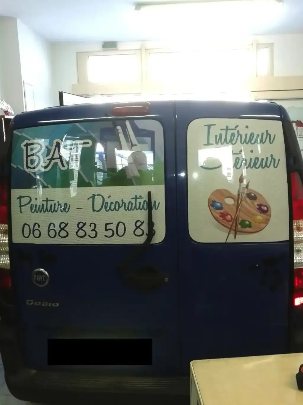 Lettrage adhésif posé à l’arrière d’une camionnette bleu nuit pour une activité de peinture.